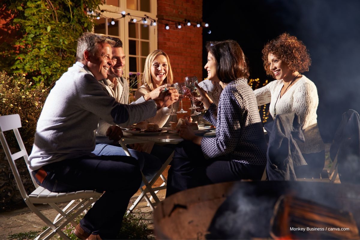 Gruppe von Meschen sitzt Abends, bei einem Glas Wein, zusammen.